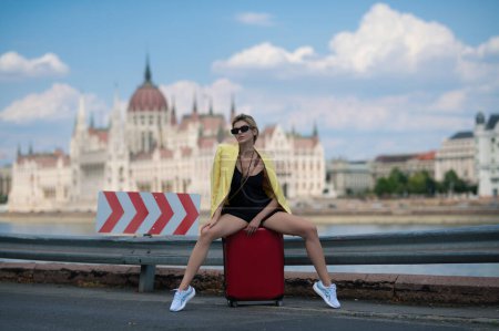Téléchargez les photos : Voyage et aventure à Budapest. Voyageur étudiante ou jeune touriste. Femme touristique avec sac de voyage marchant sur la rue de la ville en plein air. Voyager à l'étranger le week-end - en image libre de droit