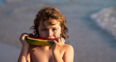 Photo for Kid eating watermelon at the beach. Child holding slice of watermelon on beach. Summer fun holiday and travel concept. Child in sea during vacation outdoors. Kid is smiling, enjoying eating fruit - Royalty Free Image