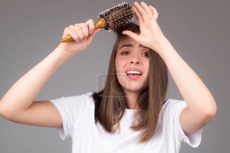 Téléchargez les photos : Hair loss woman with a comb and problem hair. Hairloss and hairs problems. Sad girl with damaged hair. Haircare and loss hair problem. Tangling hairs. Girl combing damaged hairs. Alopecia, dandruff - en image libre de droit