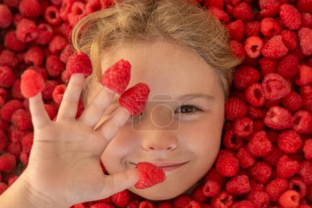 Photo for Kids face in raspberries fruits, healthy kids nutrition concept. Raspberries on fingers, summer banner - Royalty Free Image