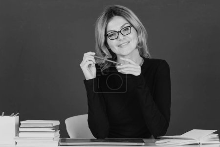 Téléchargez les photos : Souriant jolie fille blonde étudiante ou enseignante portrait sur tableau noir vert en classe au collage ou au lycée - en image libre de droit