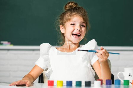 Foto de Little girls drawing a colorful pictures with pencil crayons in school classroom. Painting kids. Funny kids emotions - Imagen libre de derechos
