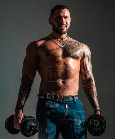 Photo for Portrait of confident man with beard and tattoo. Power. Lifestyle people concept. Attractive brutal tattooed bearded guy poses with dumbbells. Bearded man. Isolated grey background - Royalty Free Image