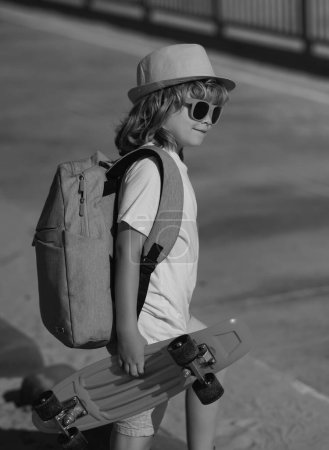 Photo for Happy stylish child in sunglasses and fashion summer hat posing with skateboard outdoor. Summer outdoor sport and lifestyle - Royalty Free Image