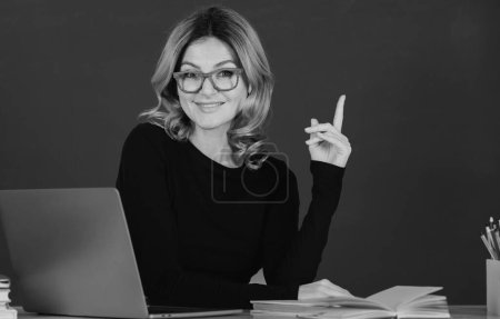 Foto de Portrait of teacher or female tutor working at table in college or high school. Young women student with pointing finger - Imagen libre de derechos