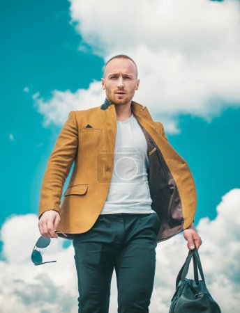 Photo for Brutal hipster boy. Lifestyle people concept. Side view portrait of confident bearded man in white t shirt.Portrait man with bag and glasses. Isolated sky background - Royalty Free Image