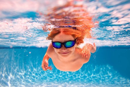 Téléchargez les photos : Enfant nageant dans la piscine sous l'eau. Enfant garçon nager sous l'eau dans la mer. Enfants jouant et plongeant dans la piscine. Les enfants drôles garçon jouent et nagent dans l'eau de mer ou de piscine. Concept vacances d'été - en image libre de droit
