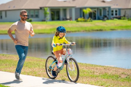 Photo for Happy fathers day. Father and son learning to ride a bicycle having fun together at Fathers day. Father teaching his son cycling on bike in american neighborhood. Father and son concept. Father - Royalty Free Image