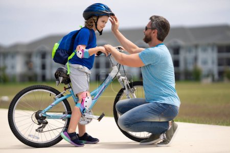 Photo for Fathers day and summer family weekend. Father helping his son to wear a cycling helmet. Child in safety helmet. Father support and helping son. Fathers day concept. Father and son friends. Child care - Royalty Free Image