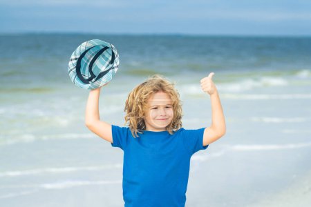 Photo for Happy child playing in the summer sea. Kid having fun at the beach. Summer vacation and kids active. Excited child with thumbs up on sea summer beach. Expressive emotional face - Royalty Free Image