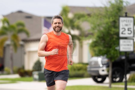 Photo for Handsome middle aged man running across american neighborhood. Athletic man running outdoor. Healthy lifestyle. Active healthy runner jogging outdoor - Royalty Free Image