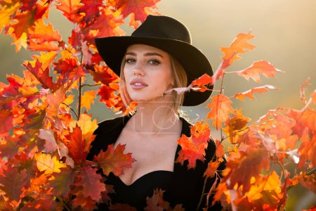 Photo for Autumn fall. Portrait young woman with autumn leafs on foliage. Beautiful girl outdoor in autumn. Sensual woman with yellow leaves in autumn. Pretty woman with leaf near face on autumnal background - Royalty Free Image