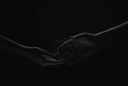 Téléchargez les photos : Two hands reaching toward. Helping hand outstretched for salvation on isolated black background. Close up of man and woman hand touch with fingers. Man and woman holding hands - en image libre de droit