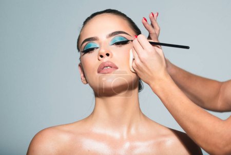 Photo for Sexy makeup for party. Makeup artist applies eye shadow. Hand of visagiste, painting cosmetics of young beauty model girl. Beautiful sensual young woman with sexy make up, close-up portrait - Royalty Free Image