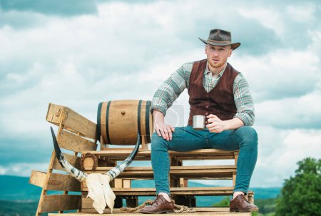 Foto de Campesino vaquero mantenga taza de café o té. La vida occidental. Retrato masculino de país americano. Campesino en el campo en la granja o rancho - Imagen libre de derechos