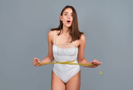 Photo for Slim woman with measuring tape around the waist line. Slim young woman measuring her waist, weight los - Royalty Free Image