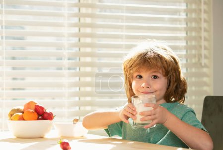 Téléchargez les photos : Les enfants mangent. Gros plan de mignon petit garçon gosse boire savoureux lait biologique avec des vitamines calcium à partir de verre. Petit enfant profiter de délicieux yaourt nutritif sans lactose. Nutrition infantile - en image libre de droit