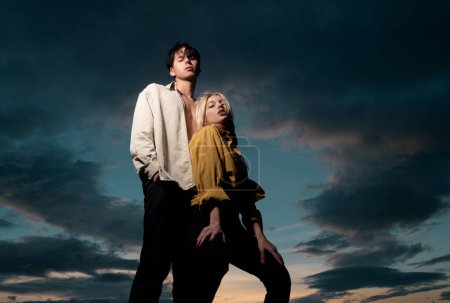 Foto de Jóvenes amantes abrazándose y abrazándose en el cielo dramático. Pareja enamorada ternura y afecto - Imagen libre de derechos