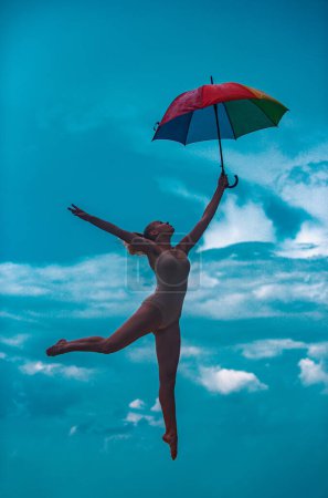 Foto de Ballet artístico. Mujer joven en forma con paraguas estirándose. Deportiva joven haciendo ejercicio de fitness, la vida sana - Imagen libre de derechos