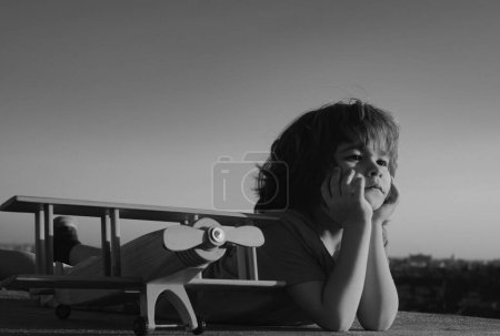 Foto de Niño feliz jugando con el avión de juguete contra el fondo del cielo azul. Lindo niño de 8 años en un día soleado de verano. Niños sueña con viajar - Imagen libre de derechos
