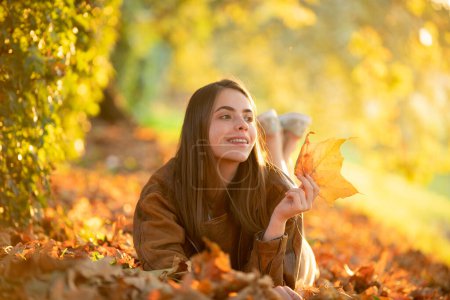 Photo for Autumn fall. Portrait young woman with autumn leafs on foliage. Beautiful girl outdoor in autumn. Sensual woman with yellow leaves in autumn. Pretty woman with leaf near face on autumnal background - Royalty Free Image