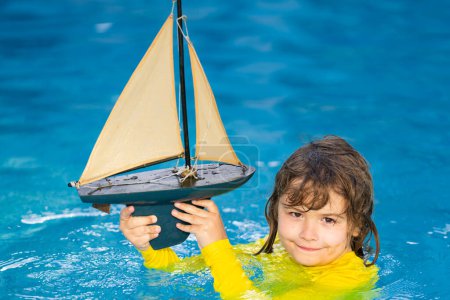 Photo for Kid play with toy sailing boat. Summer travel, kids holidays. Journey trip lifestyle yachting marine concept. Child playing with toy boat in summer sea. Dream on cruise. Travel, summer holiday - Royalty Free Image