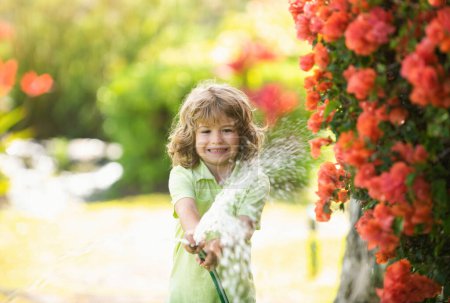 Téléchargez les photos : L'enfant arrose la plante à l'extérieur de la maison, concept d'activité d'apprentissage de la culture végétale pour les enfants et éducation des enfants à la nature - en image libre de droit