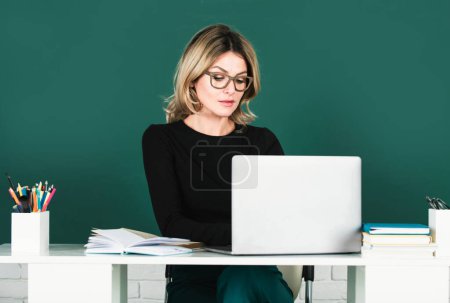 Photo for Young teacher or female student with notebook on a blank chalkboard. Female professor at school, ready to start lesson - Royalty Free Image
