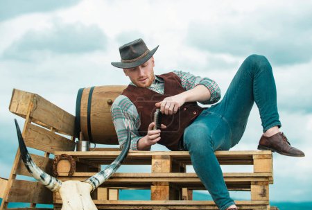 Foto de Hombre occidental sexy con sombrero de vaquero. Chico bebiendo whisky - Imagen libre de derechos