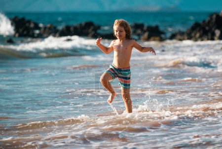 Photo for Active little boy splashing in the sea waves on a summer day during the holidays. The concept of family holidays with children - Royalty Free Image