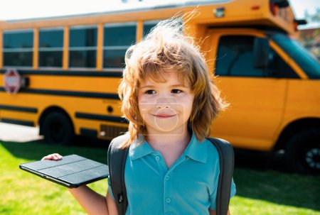 Foto de Alumno con tableta cerca del autobús escolar. Distancia social durante la cuarentena, concepto de educación en línea, escuela en casa fuera - Imagen libre de derechos