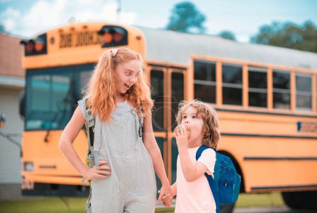 Foto de Autobús escolar y niños felices. Retrato de hermana feliz y hermano de pie juntos frente al autobús escolar - Imagen libre de derechos