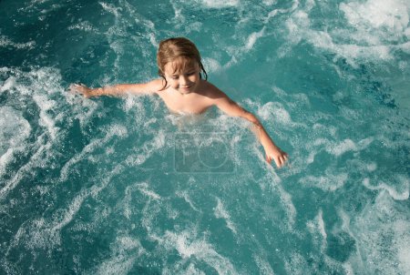 Téléchargez les photos : Enfant drôle profitant de l'été dans la piscine. Spa avec bain à remous - en image libre de droit