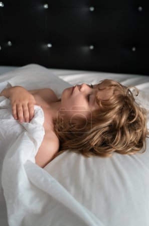 Foto de Los niños duermen. Niño tranquilo acostado en una cama mientras duerme en un dormitorio luminoso - Imagen libre de derechos