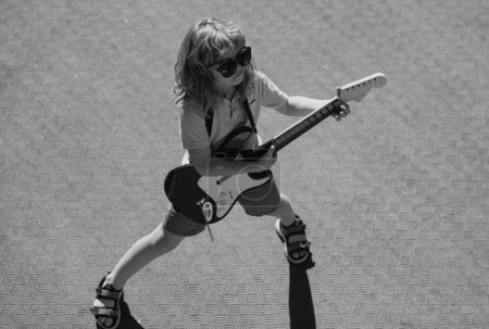 Téléchargez les photos : Des enfants de musique. Petit garçon jouant de la guitare. Rock, pop. Concept musical pour enfants - en image libre de droit