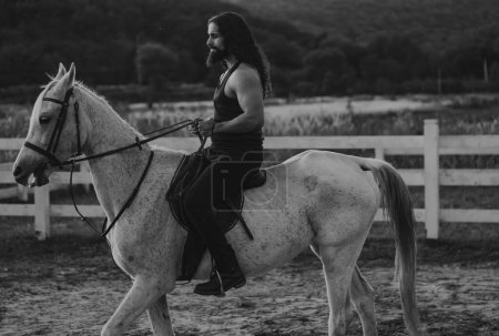 Téléchargez les photos : Un bel homme musclé à cheval. Homme monter à cheval à la ferme. Jeune jockey entraînant son cheval pour une balade - en image libre de droit