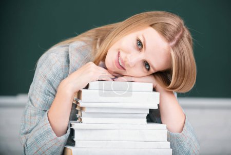 Photo for Close up portrait of cute attractive young woman student with books on blackboard background with copy space - Royalty Free Image