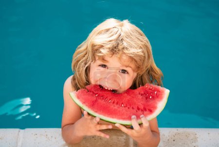Téléchargez les photos : Drôle étonnant enfant mange pastèque près de la piscine - en image libre de droit