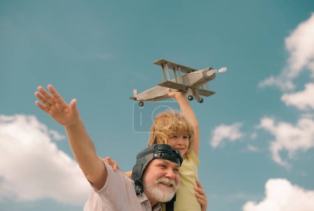 Foto de Niño niño y abuelo divertirse con avión de juguete en el cielo. Sueños infantiles de volar, infancia feliz con el abuelo - Imagen libre de derechos