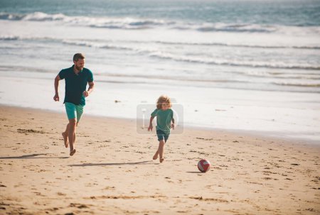 Foto de Padre e hijo juegan fútbol o fútbol en la playa. Papi con niño jugando en un día de verano - Imagen libre de derechos