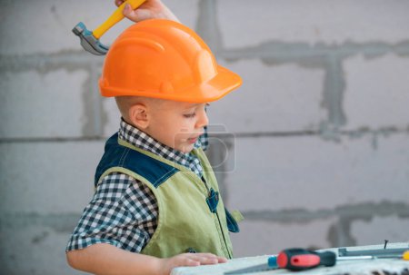 Foto de Retrato de pequeño constructor en sombreros con instrumentos para la renovación en la construcción. Constructor, carpintero con herramientas de construcción. Constructor y reparación de niños - Imagen libre de derechos