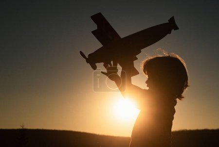 Photo for Funny child 6 year old or kid little boy pilot play with toy airplane, startup freedom and carefree. Dreams of flight. Child playing with toy airplane against the sunset sky - Royalty Free Image