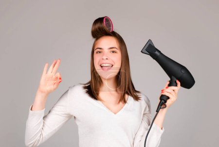 Photo for Woman with hair dryer with ok. Beautiful girl with straight hair drying hair with professional hairdryer - Royalty Free Image