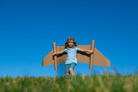 Téléchargez les photos : Garçon enfant avec des ailes au ciel imagine un pilote et rêve de voler - en image libre de droit
