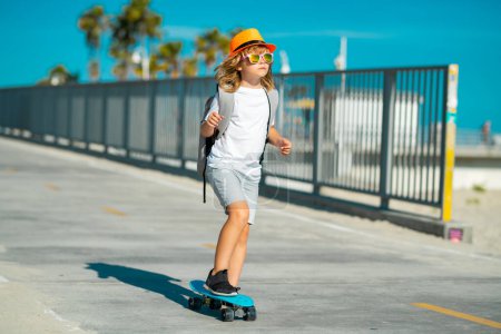 Foto de Un chico patinando en patineta. Feliz niño activo aprendiendo a equilibrarse en el skateboard jugando en la calle. Cabalgando y se ve feliz. Niño jugando surf skate o monopatín al aire libre - Imagen libre de derechos