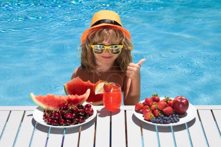 Photo for Summer child by the pool eating fruit and drinking lemonade cocktail. Summer kids. Little kid boy relaxing in a pool having fun during summer vacation. Kid relaxing on sea beach or pool - Royalty Free Image