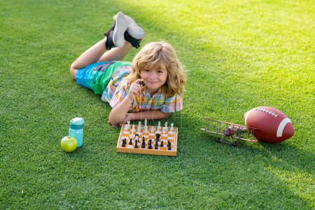 Téléchargez les photos : Jeux d'été et activités de plein air pour les enfants. Intelligent concentré et pensant enfant jouer aux échecs - en image libre de droit