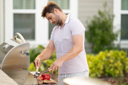 Photo for Grill cook. Chef with BBQ cooking tools. Barbecue and grill. Picnic and barbecue party. Chief cook with utensils for barbecue grill. Barbeque on holiday picnic. Man grilling a steak on BBQ - Royalty Free Image
