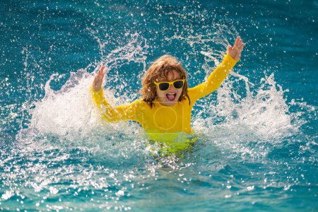 Téléchargez les photos : Enfant excité profiter des vacances d'été et des vacances d'été dans la piscine. Enfant heureux jouant dans l'eau de mer ou de piscine. Mode de vie sain des enfants. Mignon enfant éclabousser de l'eau à la piscine - en image libre de droit