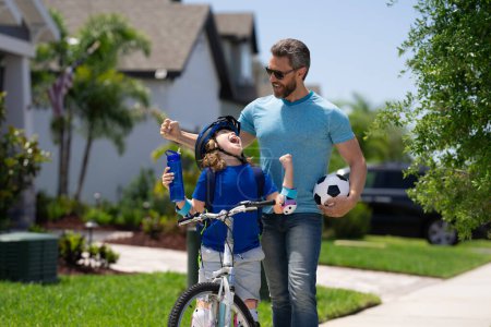 Photo for Fathers day. Happy family, men generations. Concept of friendly family and summer lifestyle. Sporty family. Excited father and son with winning gesture. Parents and children friends. Child first bike - Royalty Free Image